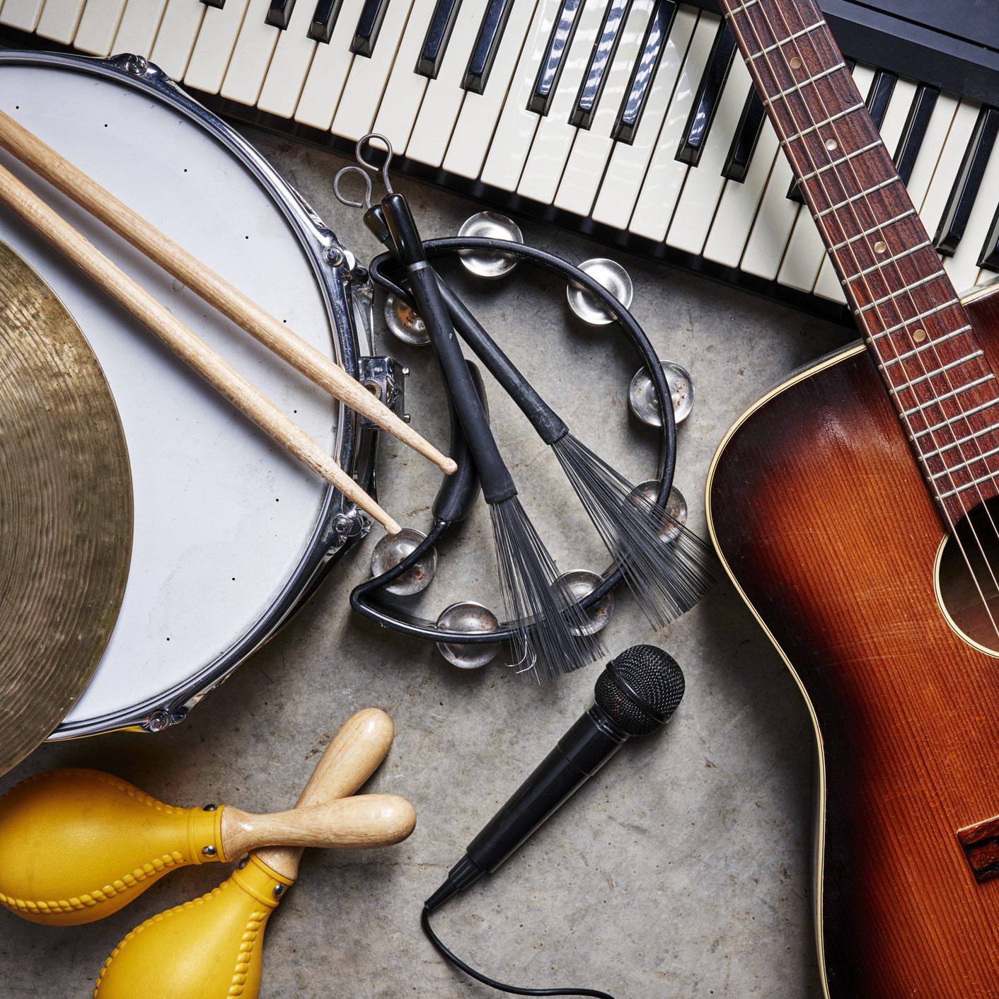 a group of musical instruments including a guitar, drum, keyboard, tambourine.